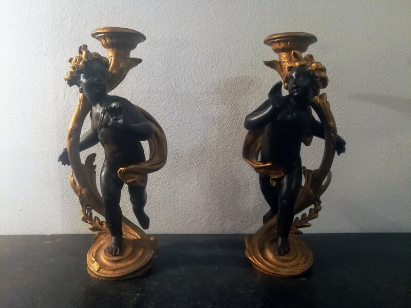 Pair of patinated black and gilt metal cherubs candlesticks